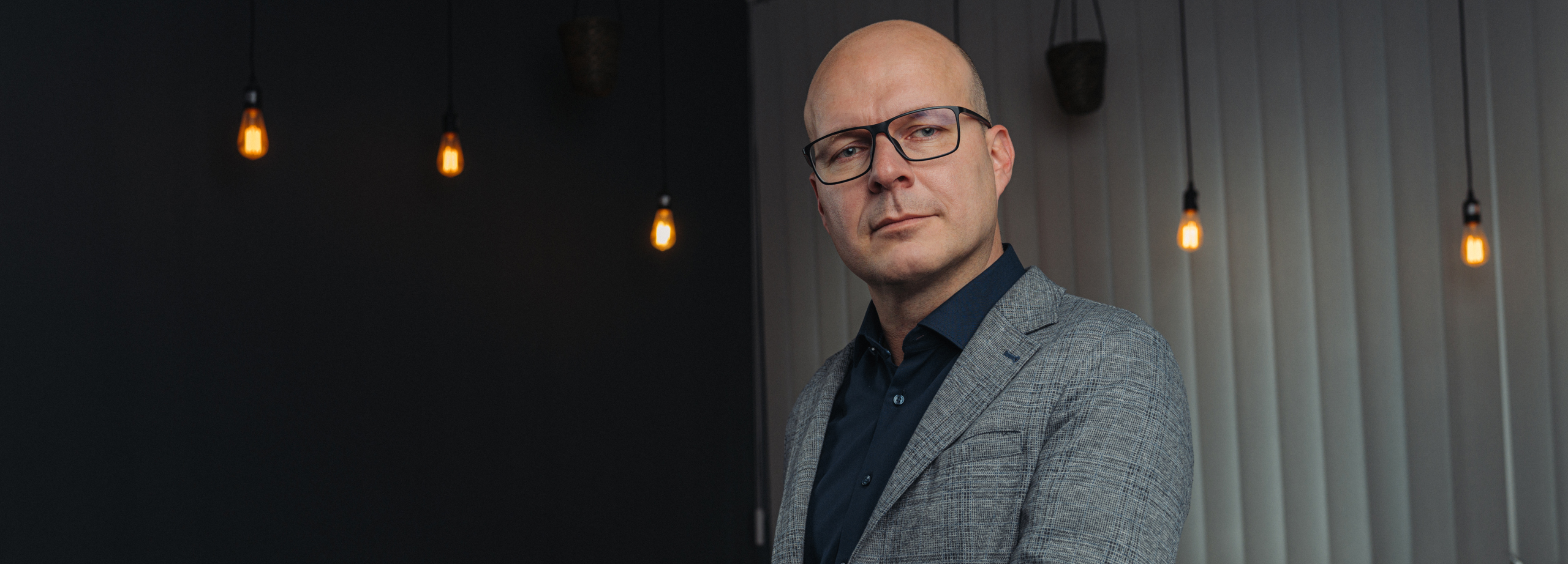Dozent mit Brille im Sakko vor stimmungsvoller Lichtinstallation